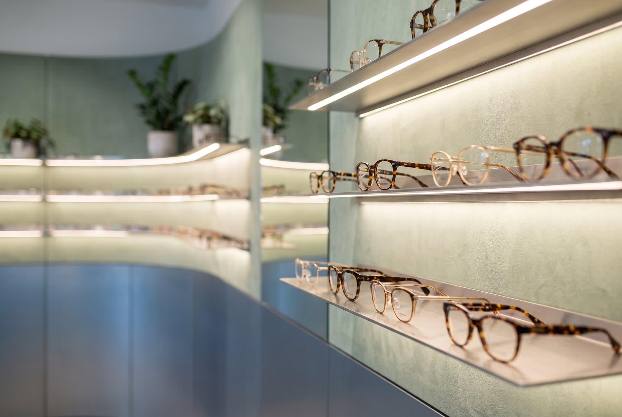 Spectacle frames displayed on illuminated optical shelves